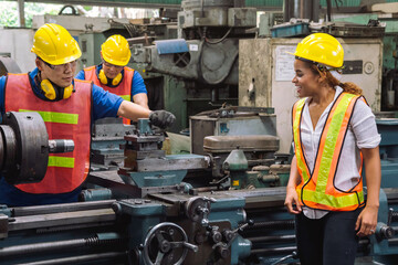 Happy Work. Engineer with Female mechanical worker with yellow safety helmet checking on production...