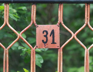 Vintage grunge square metal rusty plate of number of street address with number. Close up, brand.