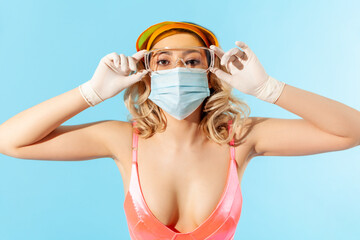 Closeup woman in swimsuit and hygienic face mask adjusting protective eyeglasses, wearing personal protective equipment to prevent coronavirus on resort, safe summer vacation in covid-19 quarantine