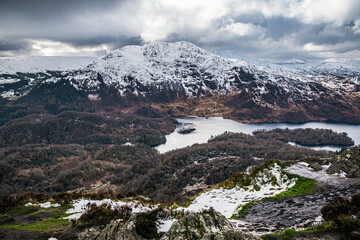 Winter Scottish view from Ben A'an overlooking Loch Katrine and snow-capped peak of Ben Venue in Scottish Highlands.