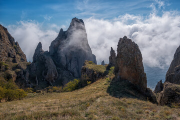 Sea fog is moving on the rocks of the Kara-Dag volcanic mountain range in the Crimea