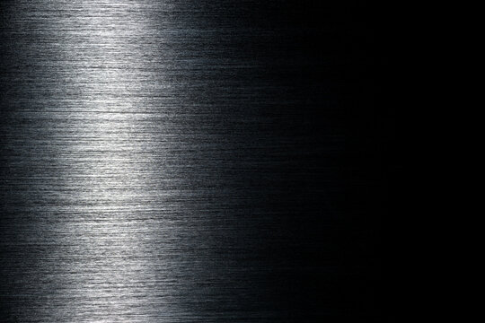 Texture of black polished anodized aluminum with light reflection on the left and free space on the right