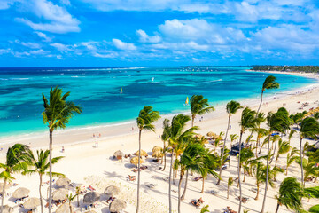 Aerial drone view of beautiful atlantic tropical beach with palms, straw umbrellas and boats. Bavaro, Punta Cana, Dominican Republic. Vacation background.