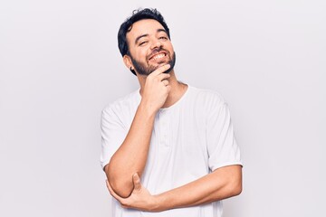 Young hispanic man wearing casual clothes looking confident at the camera with smile with crossed arms and hand raised on chin. thinking positive.