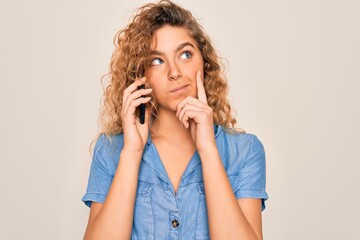 Young beautiful blonde woman with blue eyes having conversation talking on the smartphone serious face thinking about question, very confused idea