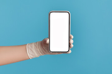 Profile side view closeup of human hand in white surgical gloves holding and showing smart phone empty display. indoor, studio shot, isolated on blue background.