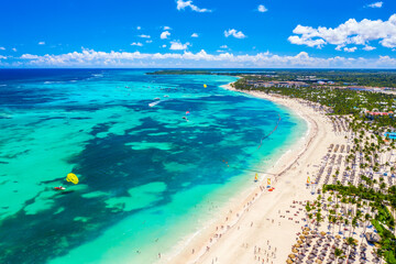 Fototapeta na wymiar Aerial drone view of beautiful atlantic tropical beach with palms, straw umbrellas and boats. Bavaro, Punta Cana, Dominican Republic. Vacation background.