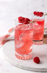 Pink rose cocktails with raspberry in crystal glass on table