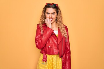 Young beautiful blonde woman pin-up with blue eyes wearing red sunglasses and jacket looking stressed and nervous with hands on mouth biting nails. Anxiety problem.