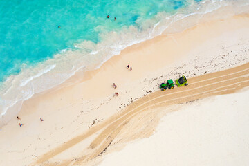Aerial drone view of tractor cleaning the beach from seaweed. Bavaro beach in Punta Cana, Dominican...