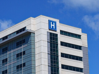 large modern building with blue letter H sign for hospital - 354152331