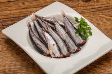 Anchovies in the bowl served basil leaves
