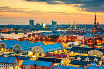 Naklejka premium Piękna panorama z lotu ptaka na centrum Rygi i most Vansu nad Dźwiną podczas niesamowitego zachodu słońca. Widok na oświetlone miasto Ryga, stolica Łotwy.