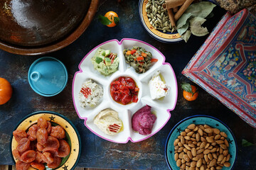 Sauces and salads mix in a ceramic painted Oriental plate in the center of the table Mandarin dried apricots nuts almonds Eastern cuisine