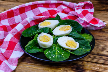 Spinach leaves and halved boiled eggs on a black plate