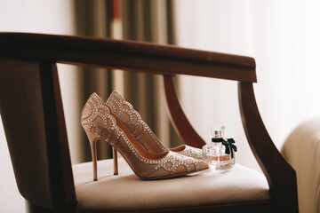 Hochzeitsschuhe für Damen sind beige oder hell mit Strasssteinen. Hochzeit modische bequeme oder unbequeme Schuhe. Flasche mit Parfüm oder Eau de Toilette. © Наталья Трофимова