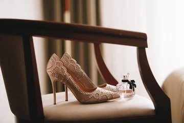 Hochzeitsschuhe für Damen sind beige oder hell mit Strasssteinen. Hochzeit modische bequeme oder unbequeme Schuhe. Flasche mit Parfüm oder Eau de Toilette. © Наталья Трофимова