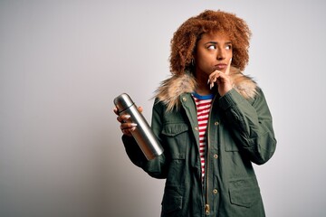 Young African American afro tourist woman with curly hair holding thermo with water serious face...