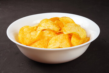 potato chips in a white bowl on a dark background