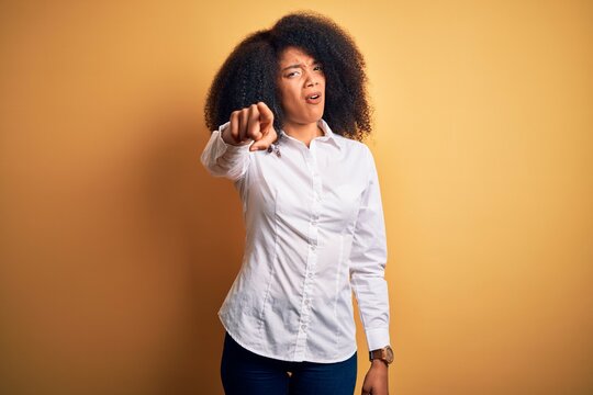 Young beautiful african american elegant woman with afro hair standing over yellow background pointing displeased and frustrated to the camera, angry and furious with you