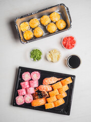 Set of sushi rolls in delivery plastic boxes on white background