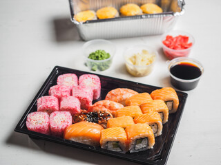 Set of sushi rolls in delivery plastic boxes on white background