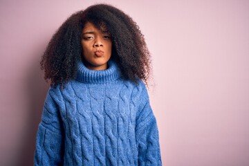 Young beautiful african american woman with afro hair wearing winter sweater over pink background depressed and worry for distress, crying angry and afraid. Sad expression.