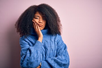 Young beautiful african american woman with afro hair wearing winter sweater over pink background thinking looking tired and bored with depression problems with crossed arms.
