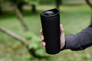 Black thermo cup on the street. Eco friendly
