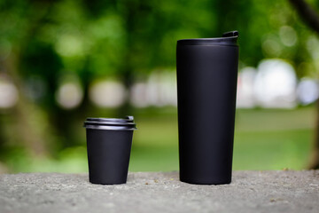 Comparing thermo cup with disposable paper coffee cup over green background