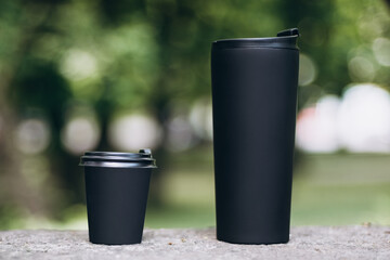 Comparing thermo cup with disposable paper coffee cup over green background