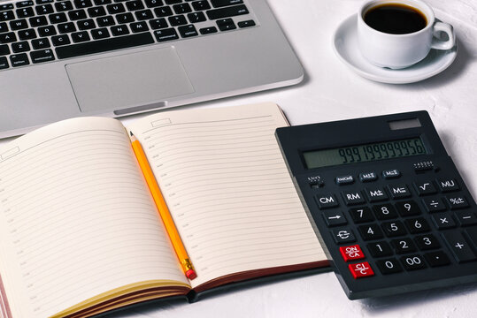 Calculator, a diary, an open laptop, a Cup of coffee, and a notebook on the desktop. Accounting, Finance and business