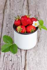 fresh strawberries with flowers and leaves on  wooden background with copy space