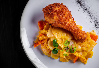 Roasted chicken leg and vegetables in white plate on black wooden table background
