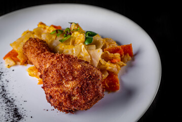 Roasted chicken leg and vegetables in white plate on black wooden table background