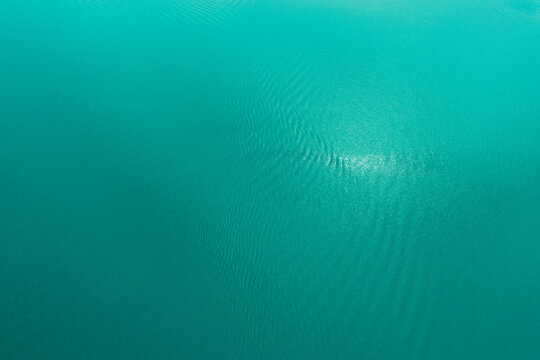 Azure Texture of the surface of lake water. Tropical calm background for design. Aerial shot top to bottom of the Azure sea with waves. High quality photo.
