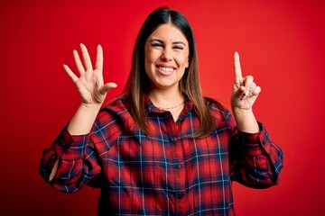 Young beautiful woman wearing casual shirt over red background showing and pointing up with fingers number six while smiling confident and happy.