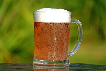 A closeup of a glass of cold beer on a hot sunny day
