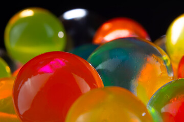 multi-colored silicone gel balls in a glass on a black background