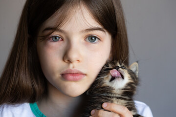 little girl holds a kitten in her arms. The child is allergic to cats, red eyes.