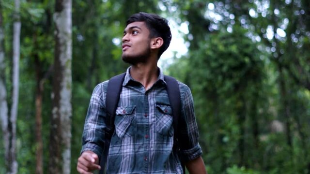 young man tourist walking through the woods with backpack concept travel tourism