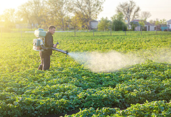 A farmer sprays a solution of copper sulfate on plants of potato bushes. Use chemicals in...