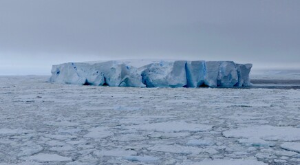 Large blue iceberg at edge of pack ice in antarctic ocean, Antarctica