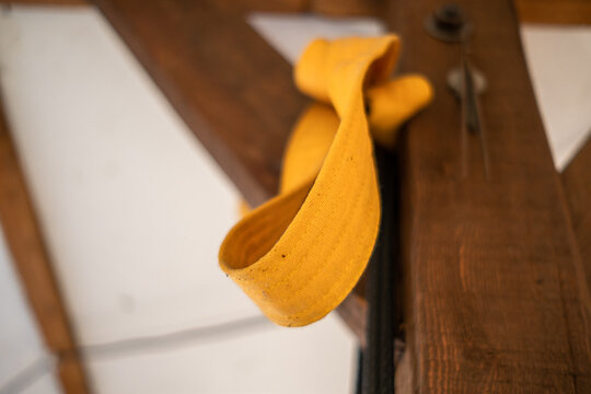 Low Angle View Of Yellow Karate Belt Knotted To Wooden Beam