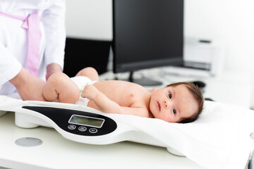 Close-up of a doctor checking weight of cute little baby. Healthcare concept