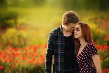 A beautiful young couple embrace in a poppy field at sunset. Space for text. Place to copy. Close up. Outdoor. Love and relationships