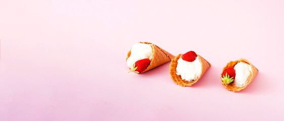 Ice cream in waffle cones with fresh strawberries on pink background. National ice cream day 19 july or hello summer concept. Close-up