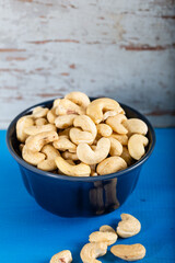Cashew in a ceramic bowl on a white wooden background.