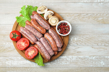 raw grilled sausages on a wooden round Board with tomatoes and mushrooms