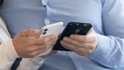 Crop close up of man and woman hold modern smartphones browsing wireless internet on gadgets, couple use cellphones, share social media content on electronic devices, new technology concept